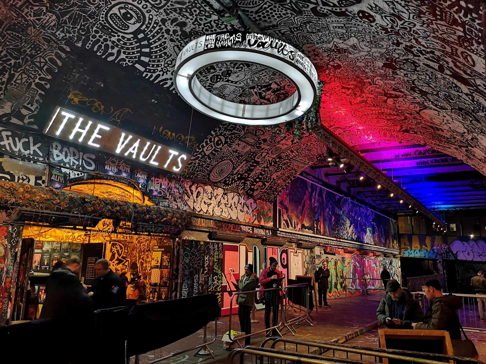 The graffiti-covered tunnel entrance to the Vaults venue, lit sign reading THE VAULTS beneath a glowing ring light